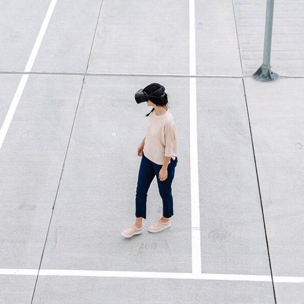 Woman walking on a parking lot with VR glasses.